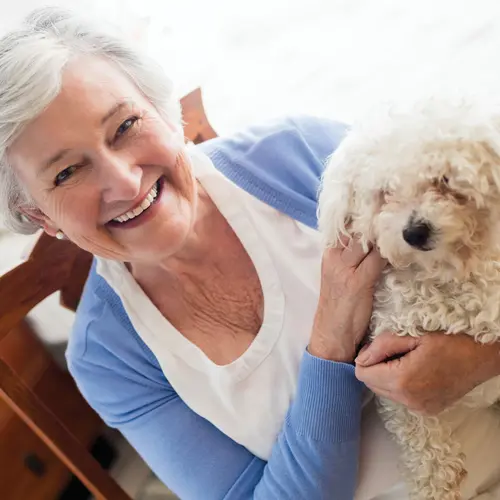 Senior woman holds a curly haired puppy / Une femme âgée tient un chiot à poil frisé