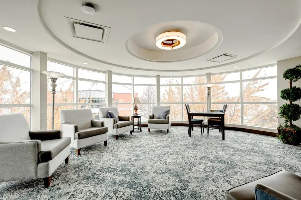 Salon avec fauteuils et grandes fenêtres à Chartwell Oasis St-Jean / Lounge with armchairs and large windows at Chartwell Oasis St-Jean