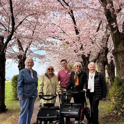 Residents standing on a path beneath blooming cherry blossoms / Résidents debout sur un sentier sous des cerisiers en fleurs