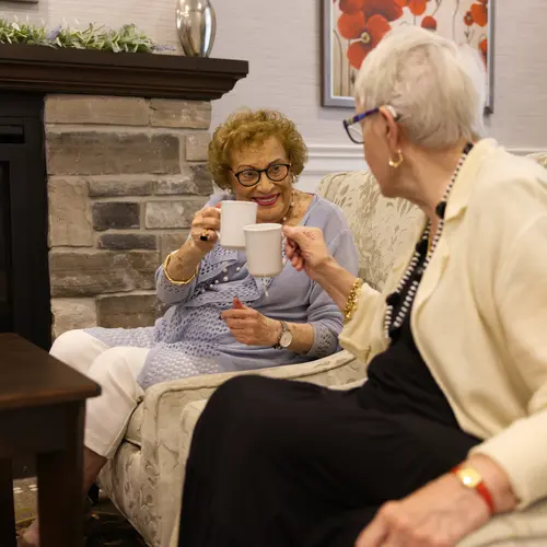 Two senior women posting their coffee cups with happy smile / Deux femmes âgées posant leurs tasses de café avec un sourire heureux