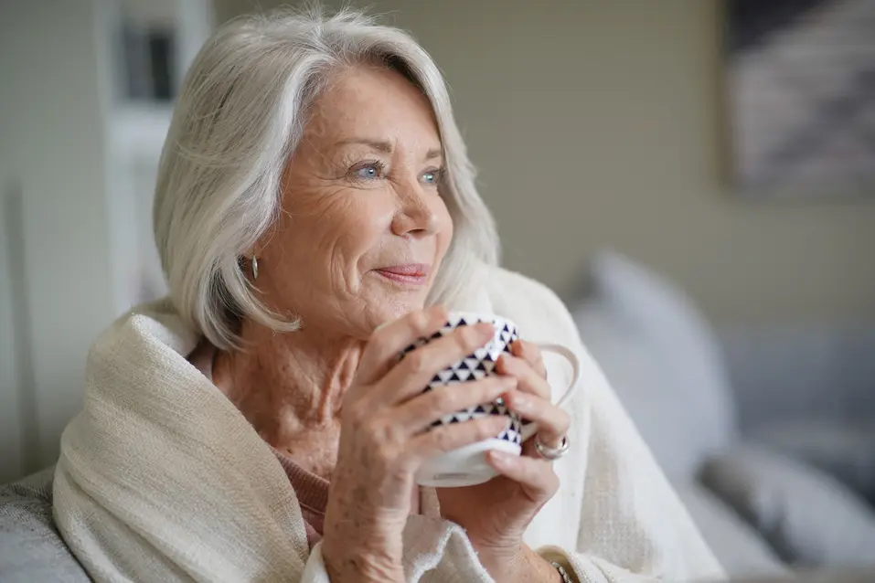 Senior woman with white hair, relaxed and drinking from a coffee cup