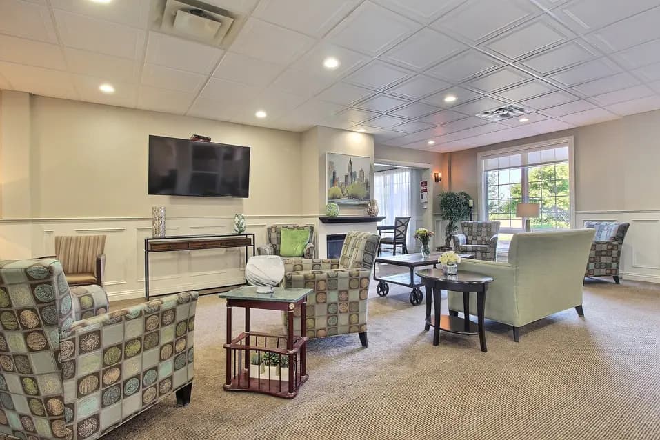 Cozy lounge area with armchairs and large windows at Chartwell Empress Kanata / Salon confortable avec fauteuils et grandes fenêtres à Chartwell Empress Kanata