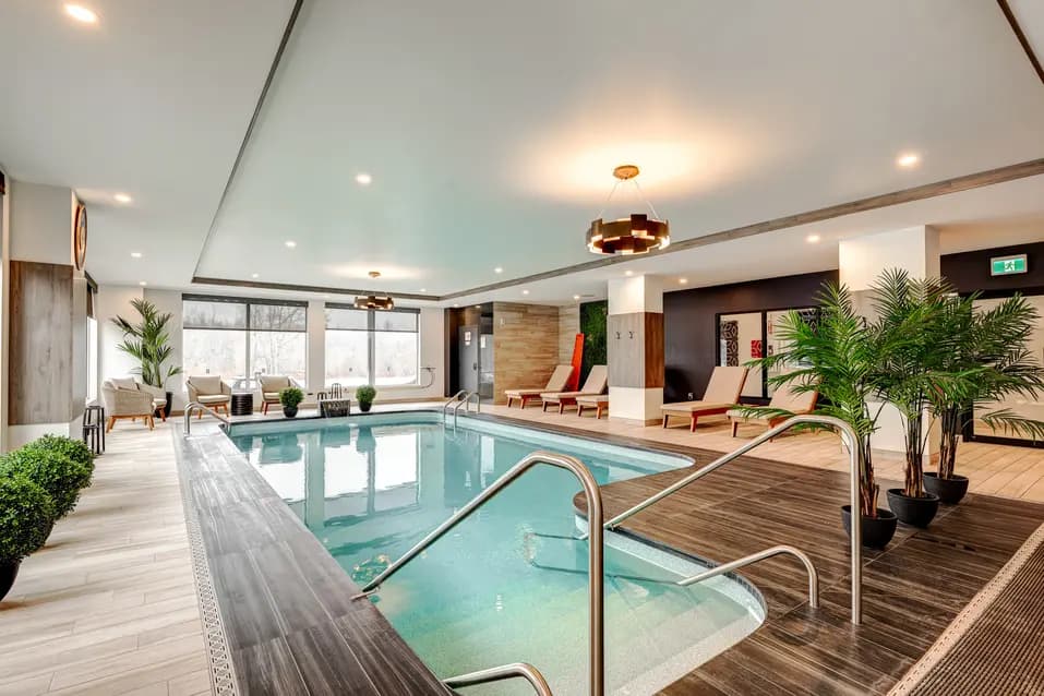 Piscine intérieure avec éclairage élégant et chaises longues, Chartwell Des Chutes / Indoor pool with stylish lighting and lounge chairs, Chartwell Des Chutes