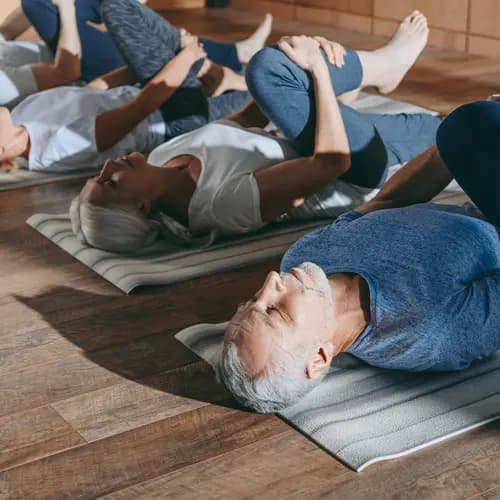 group of senior people stretching in yoga mats in studio