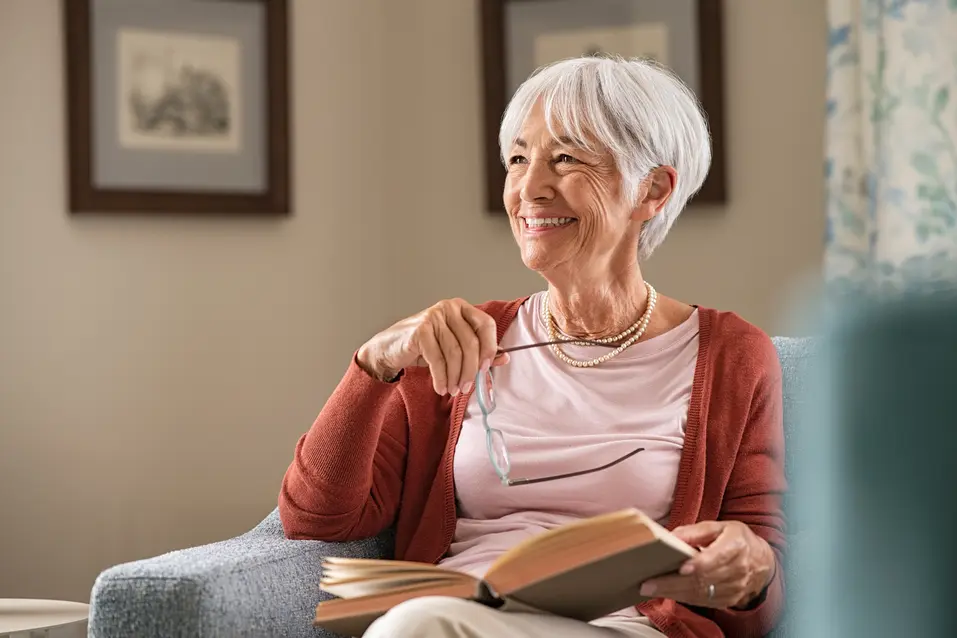 smiling senior woman with wooden cane looking at camera in apartment