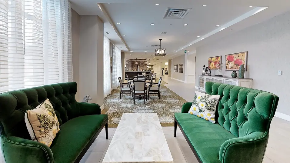 Common space area with table and green couches at Chartwell Fraser Terrace