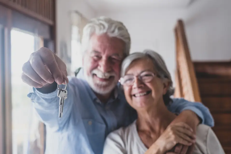 Senior couple proudly showing up a key / Un couple âgé montrant fièrement une clé