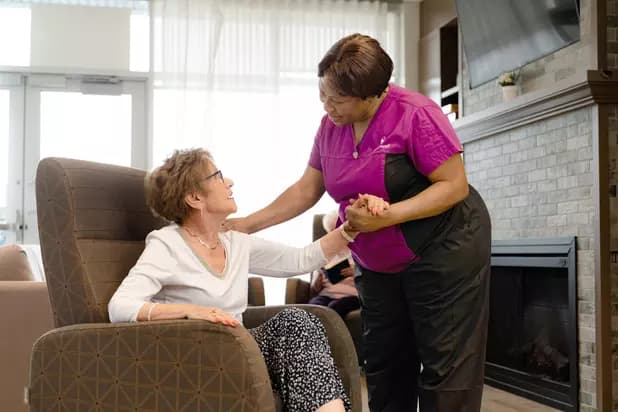 Chartwell Care staff chatting with the senior resident by the fire place / Le personnel de Chartwell Care discute avec la résidente âgée près de la cheminée