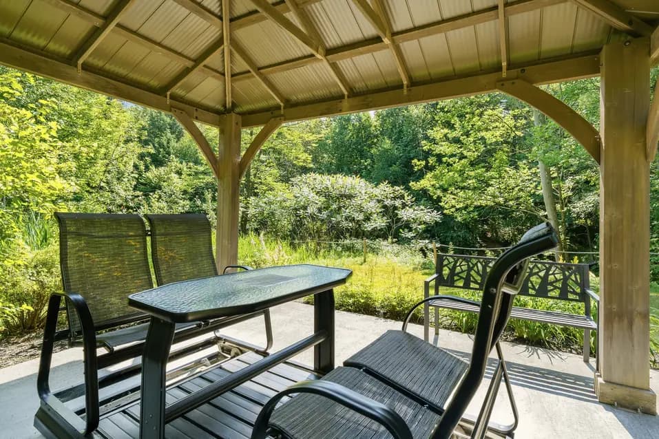 Pergola extérieure avec coin détente entouré de verdure à Chartwell Des Rivières / Outdoor gazebo seating area surrounded by greenery at Chartwell Des Rivières