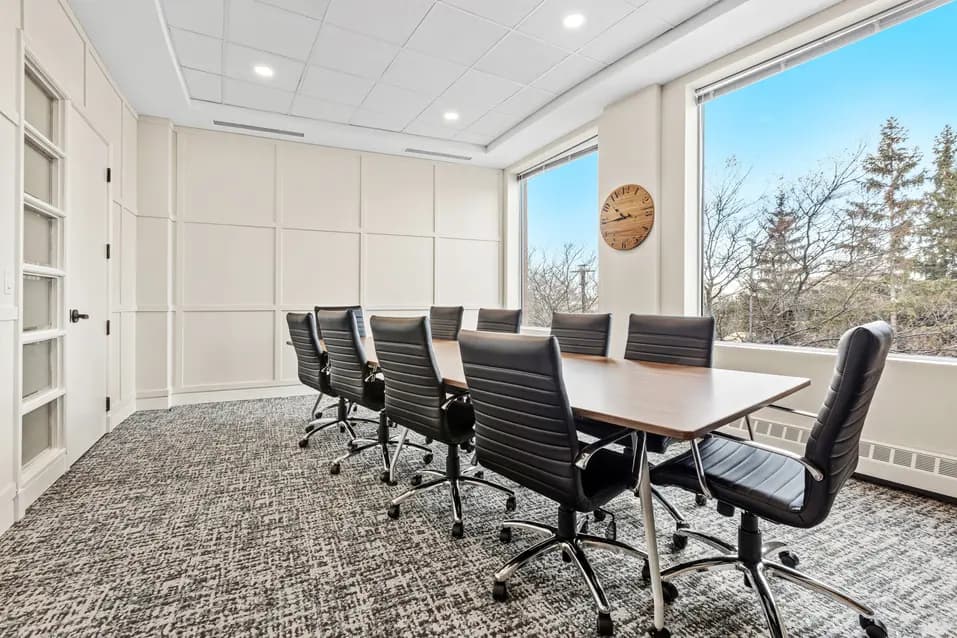 Meeting room with long table and black chairs at Chartwell Stillwater Creek / Salle de réunion avec grande table et chaises noires à Chartwell Stillwater Creek