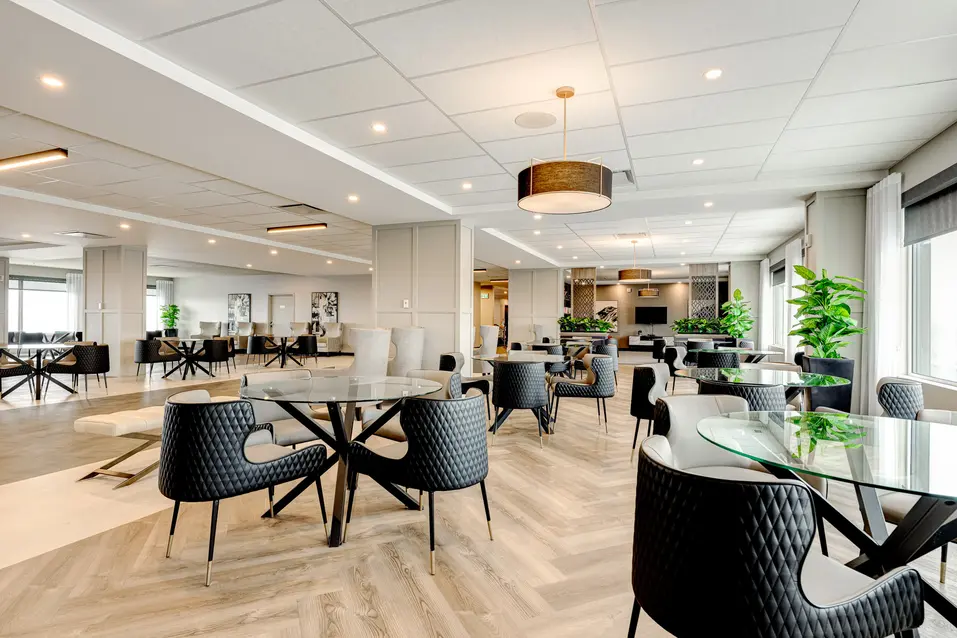 Salle commune spacieuse avec tables rondes et chaises modernes, Chartwell Des Chutes / Spacious common area with round tables and modern chairs, Chartwell Des Chutes