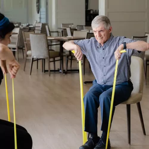 Senior resident exercising on chair with the instructor