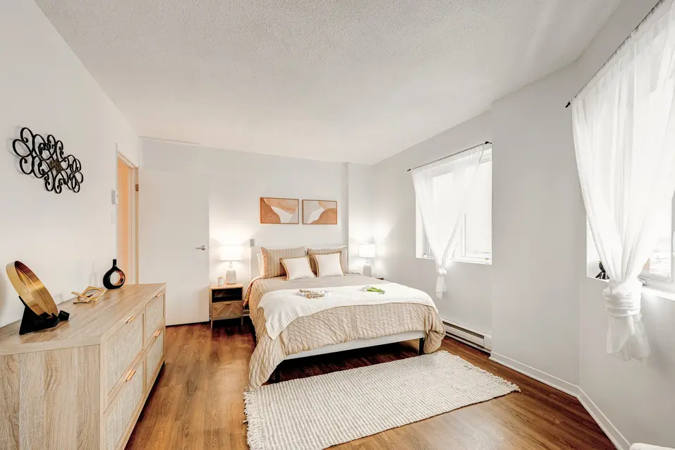 Grande chambre lumineuse avec lit beige à Chartwell Les Tours Angrignon / Large bright bedroom with beige bed at Chartwell Les Tours Angrignon