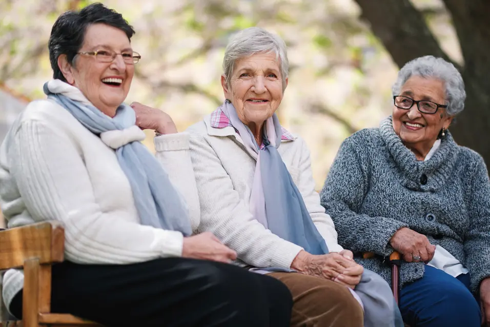 Happy old women sitting on bench in park smiling happy life long friends enjoying retirement together.