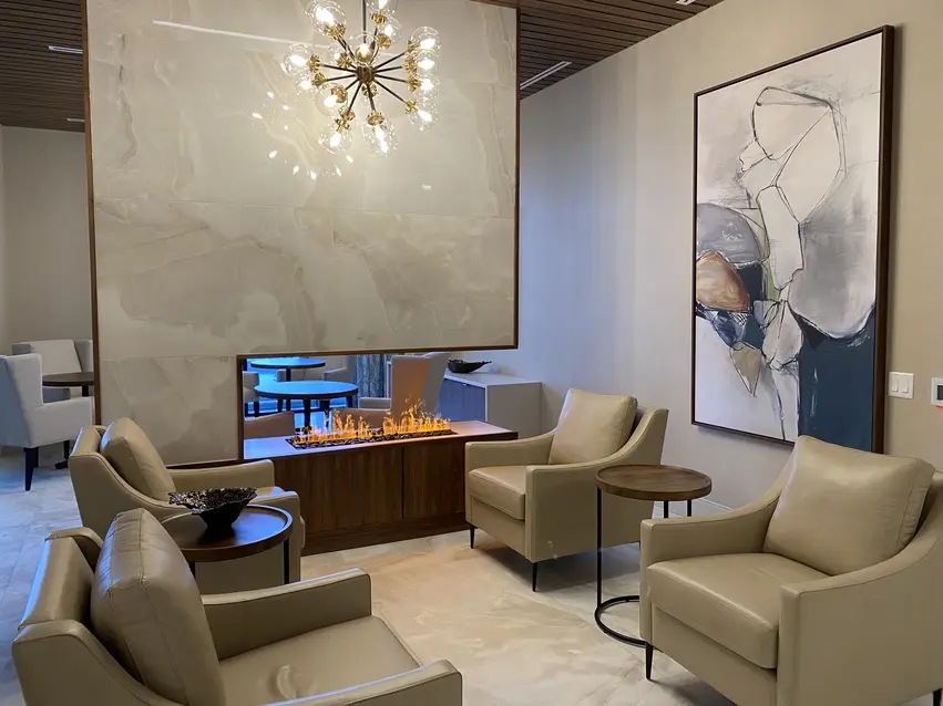 Contemporary lounge with feature fireplace and comfortable chairs at Chartwell Riverstone / Salon contemporain avec foyer décoratif et fauteuils confortables à Chartwell Riverstone