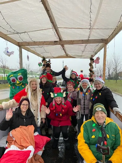 Group of seniors and caregivers wearing Christmas outfits celebrating an outdoor activity