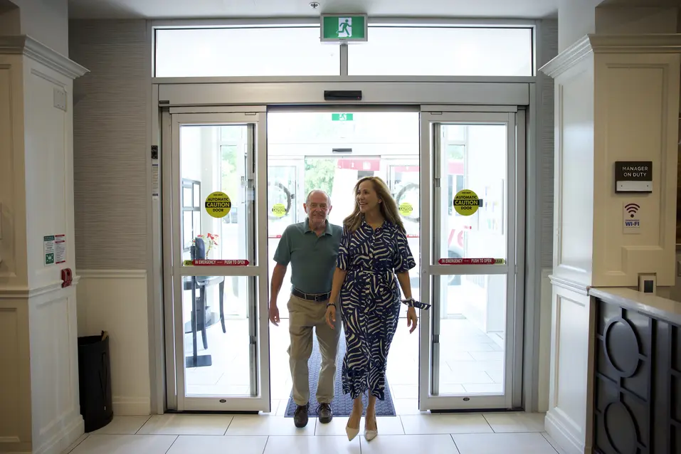 Senior couple walking through the entrance of a Chartwell Residence / Couple âgé franchissant l'entrée d'une résidence Chartwell