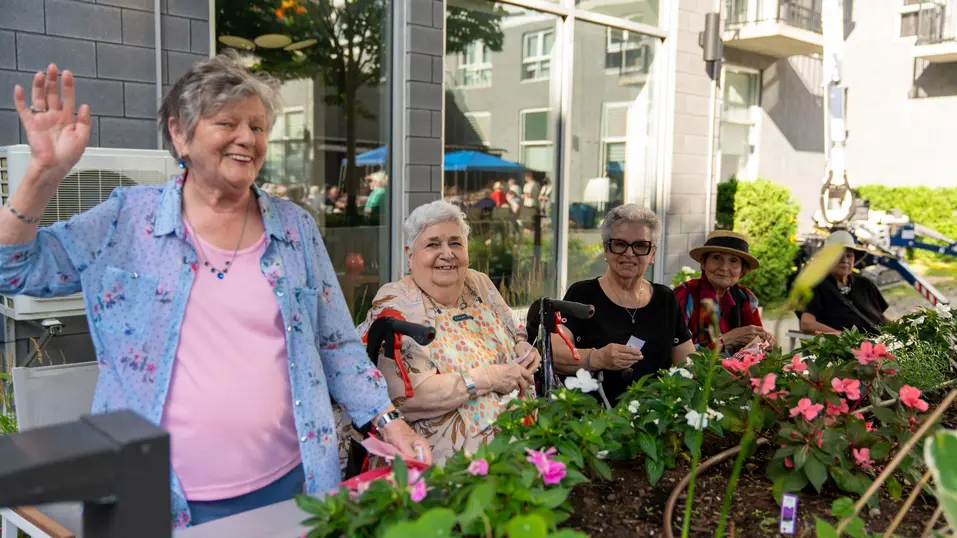 Residents gardening together around flower beds / Résidents faisant du jardinage autour de plates-bandes fleuries