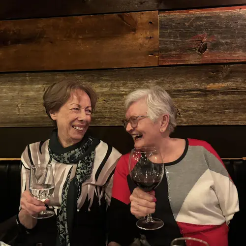 Residents holding wine glasses at a dinner table / Résidentes tenant des verres de vin à une table de restaurant