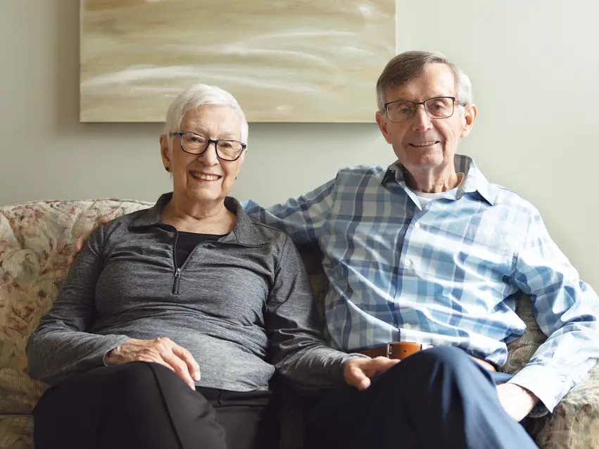 Senior couple confidently sitting on a couch / Un couple de personnes âgées, assis nonchalamment sur un canapé