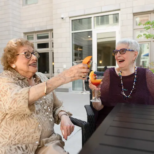 Two senior ladies smiling and cheersing