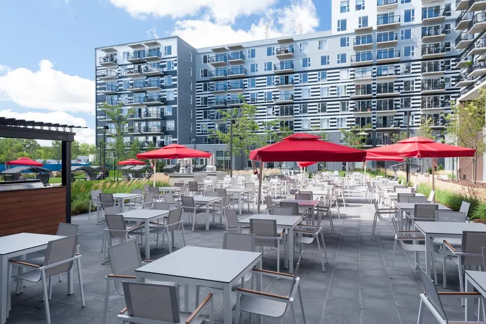Salon extérieur avec tables et parasols chez Chartwell Rosemont le Quatiers / Outdoor sitting area with tables and parasols at Chartwell Rosemont le Quatiers