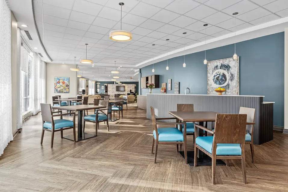 Modern bistro with tables and blue chairs at Chartwell Stillwater Creek / Bistro moderne avec tables et chaises bleues à Chartwell Stillwater Creek