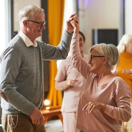 Group of smiling senior people dancing while enjoying activities in retirement home, copy space