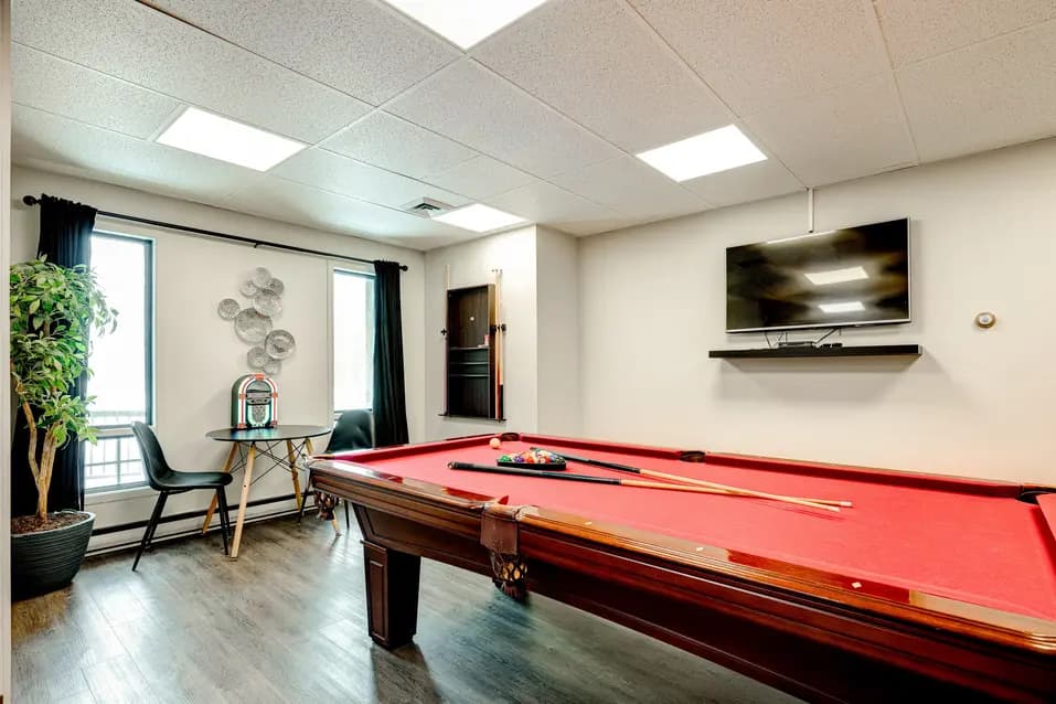 Salle de billard avec table rouge et télé murale à Les Écores / Billiards room with red pool table and wall‑mounted TV at Les Écores