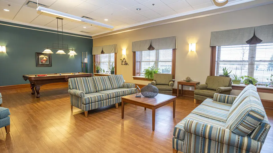 Bright common room with striped sofas and green armchairs at Chartwell Westhill / Salle commune lumineuse avec canapés rayés et fauteuils verts à Chartwell Westhill