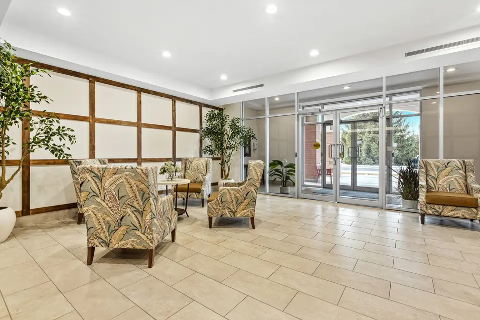 Spacious lobby with armchairs and decorative wall panels at Chartwell Stillwater Creek / Hall spacieux avec fauteuils et panneaux décoratifs à Chartwell Stillwater Creek