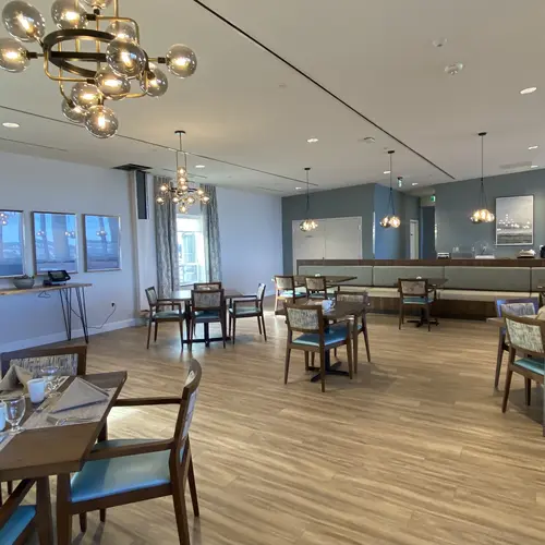 Large dining room with modern lighting and teal accents at Chartwell Riverstone / Grande salle à manger avec éclairage moderne et accents sarcelle à Chartwell Riverstone