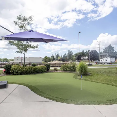 Outdoor putting green with purple umbrella at Chartwell Dorchester Terrace / Terrain de golf miniature extérieur avec parasol à Chartwell Dorchester Terrace