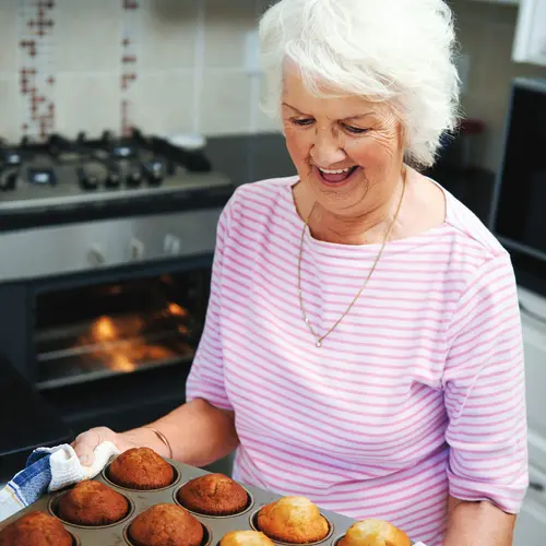 Senior woman holding a tray of freshly baked muffins