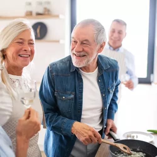A group of seniors are enjoying cooking together while having a glass of champaign / Un groupe de personnes âgées prend plaisir à cuisiner ensemble tout en buvant un verre de champagne