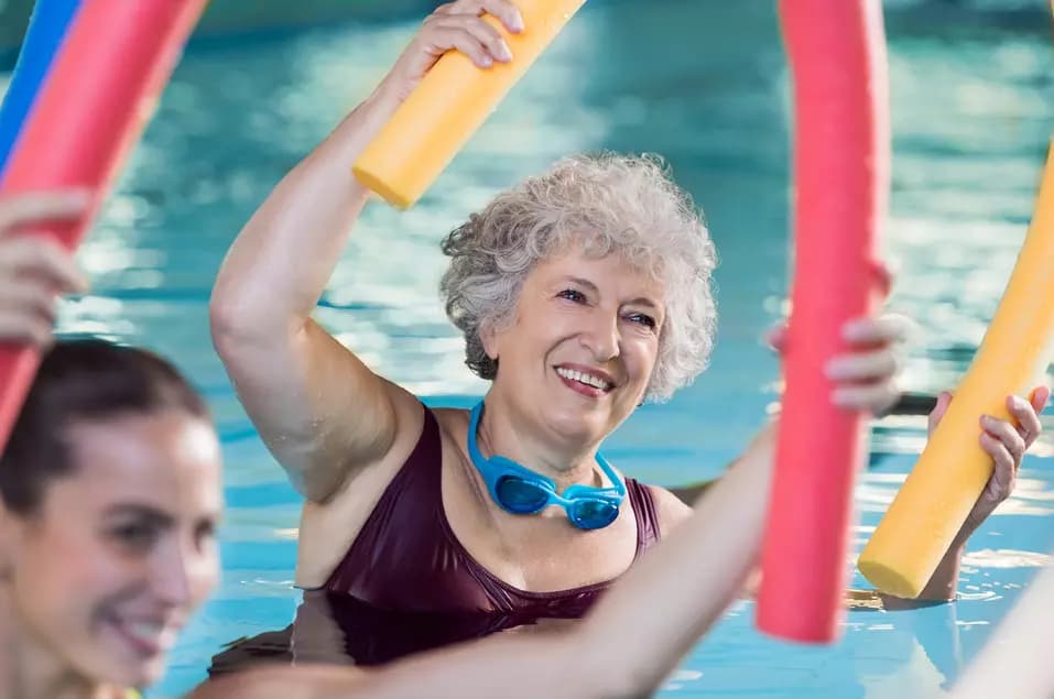 Smiling senior woman taking a n aqua aerobic class / Une femme âgée souriante suivant un cours d'aquagym