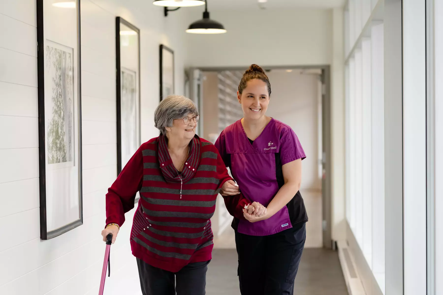 Chartwell Care staff helping senior resident walk by holding her hand
