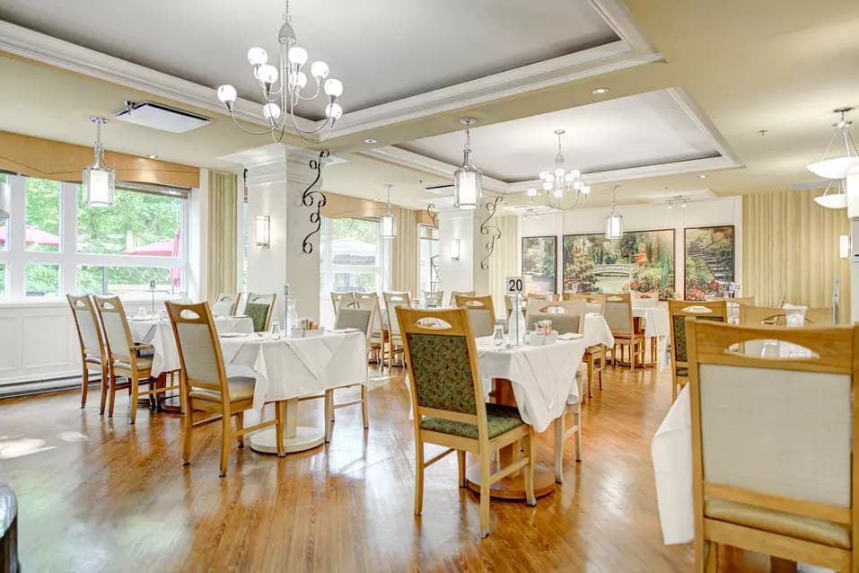 Salle à manger avec tables et chaises fenêtres et magnifique murale Chartwell Appartements de Bordeaux résidence pour retraités