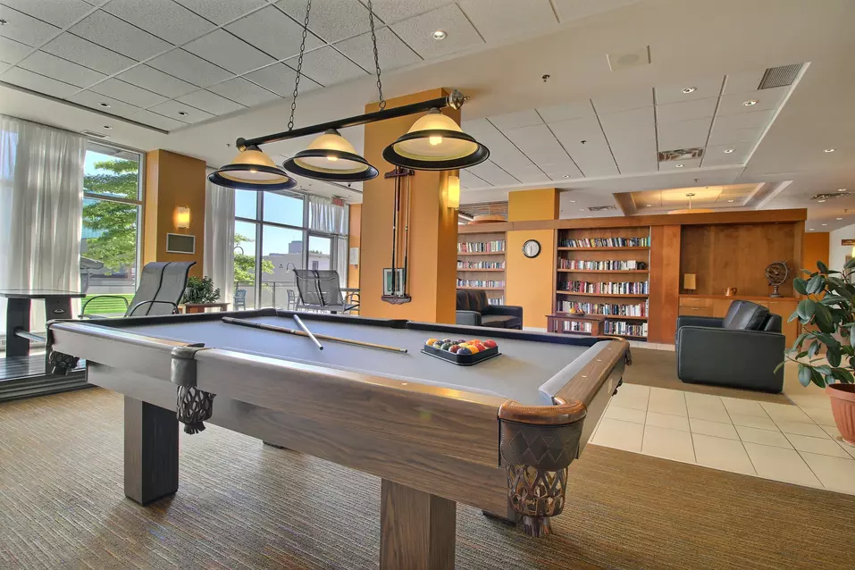Table de billard avec balançoires intérieures et bibliothèque Chartwell Jardins Notre-Dame résidence pour retraités retirement residence pool table with interior swings and library