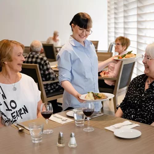 Chartwell server serving food to senior resident / Un serveur de Chartwell sert de la nourriture à une personne âgée