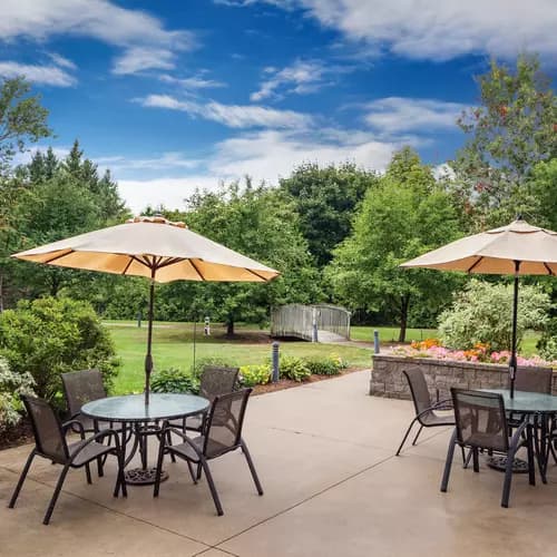 Gorgeous outdoor greenspace with walking paths and patio furniture at Chartwell Barton Retirement Residence.