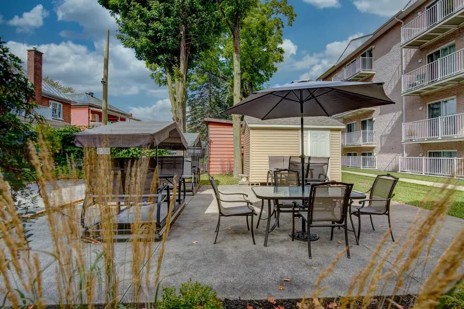 Cour extérieure avec balançoires tables et parasols Chartwell Notre-Dame de Victoriaville résidence pour retraités