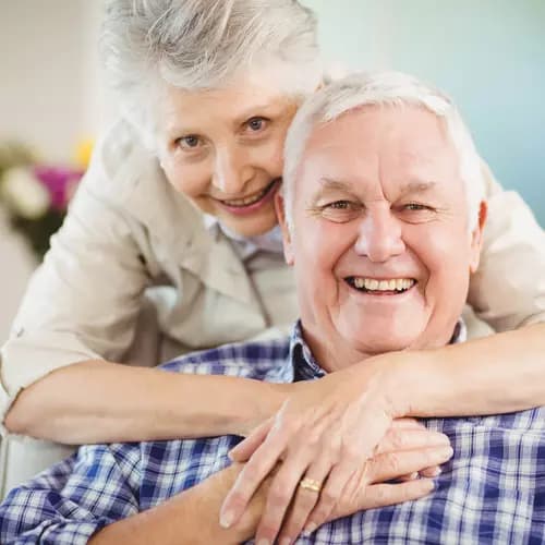 Senior couple embracing, man sitting, woman embraces man / Couple de seniors s'embrassant, homme assis, femme embrassant l'homme