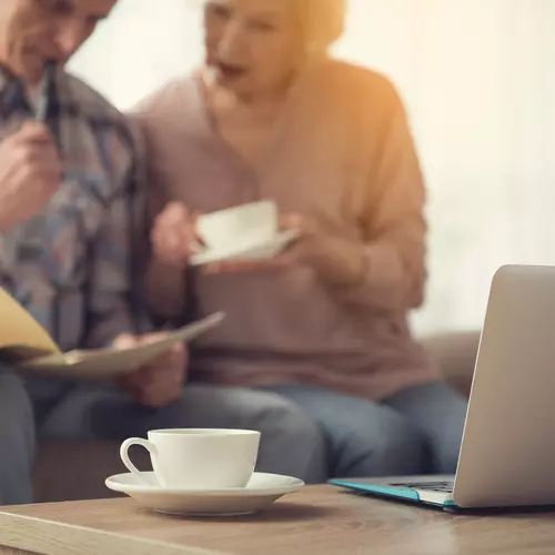 Senior couple blurred in the background with coffee cup in the foreground. Couple de seniors flou à l'arrière-plan et tasse de café au premier plan.
