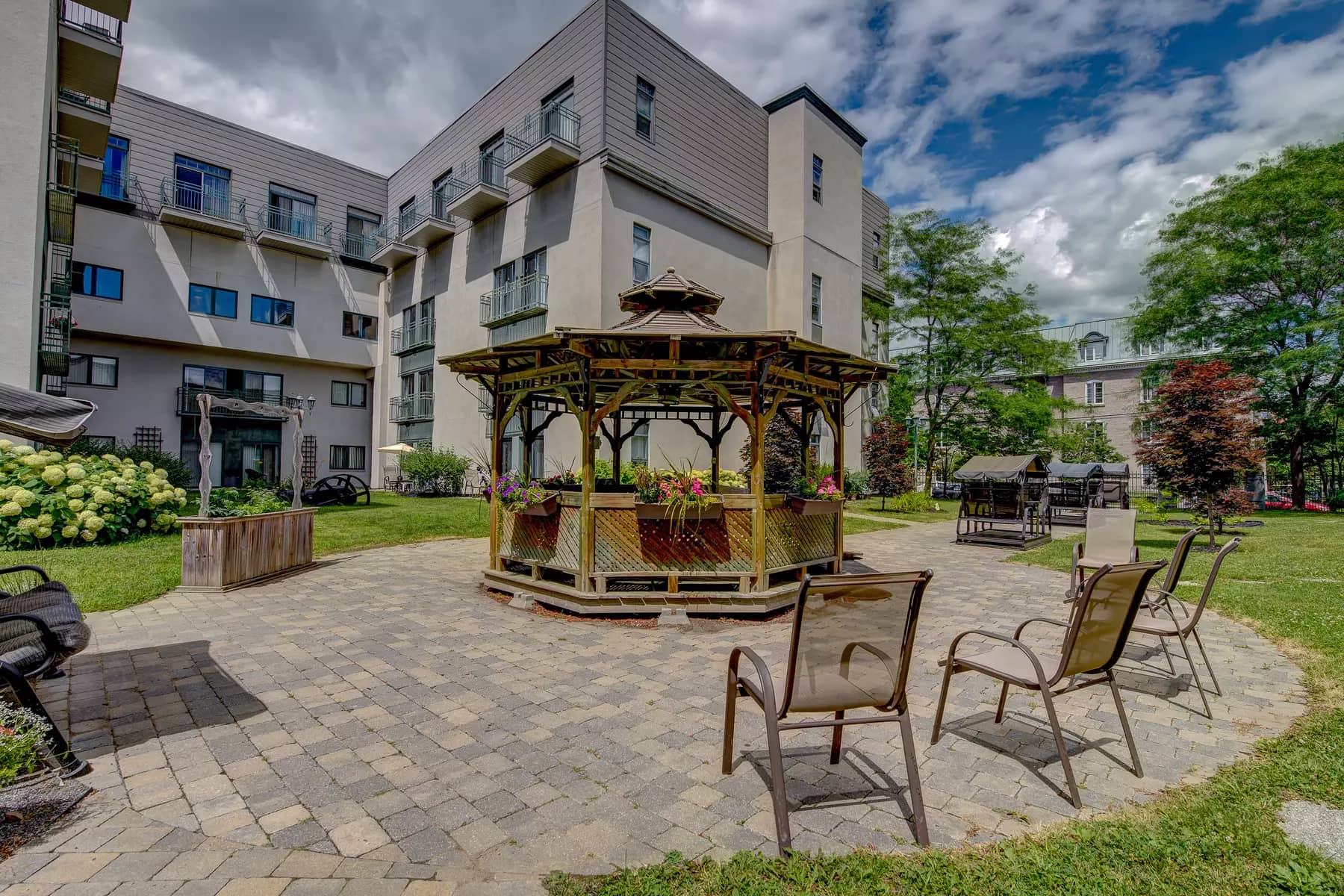 Cour extérieure avec belvédères, chaises et balançoires Chartwell Jardins de la Gare résidence pour retraités