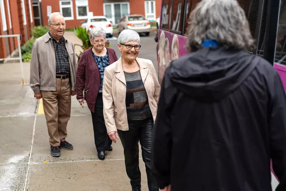 Senior residents at Chartwell residence are boarding a shuttle bus and getting greeted by the Chartwell staff / Les résidents âgés de la résidence Chartwell montent à bord d'une navette et sont accueillis par le personnel de Chartwell