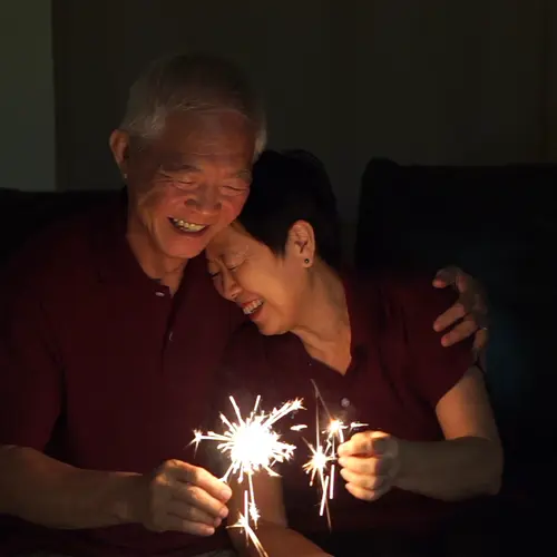 Asian senior couple celebrating together at home sparkles firework